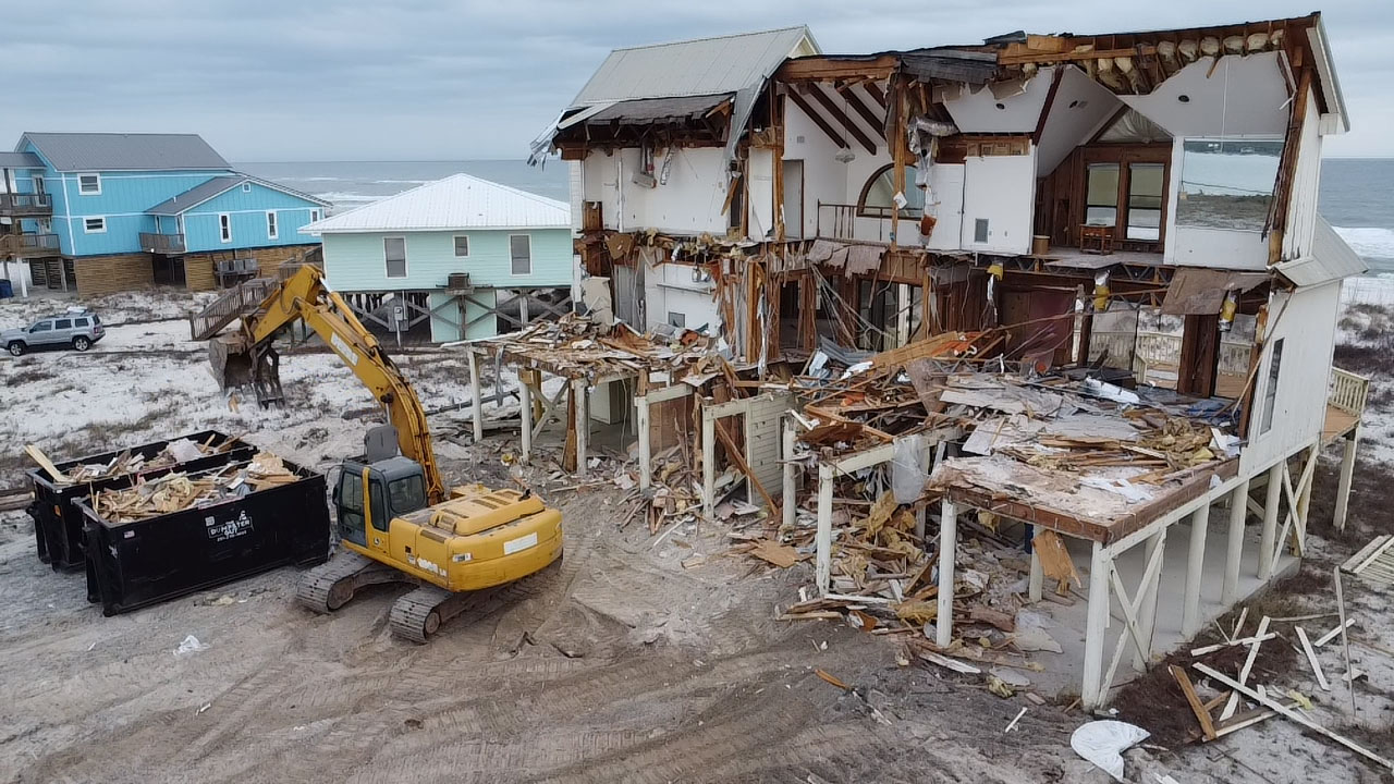 A house coming down beside a loaded container
