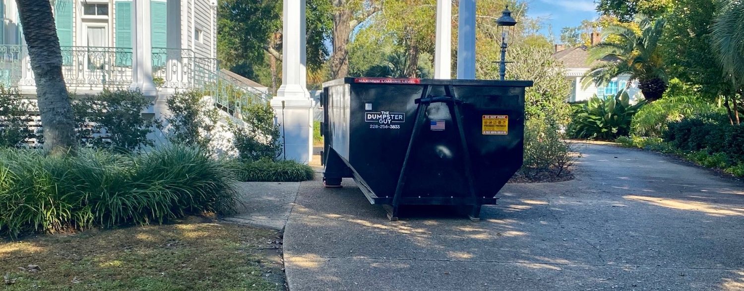 A Dumpster Guy roll-off container standing on a residential driveway