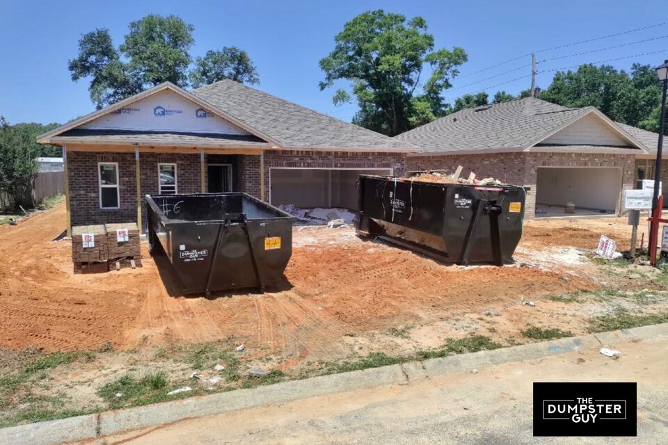 Two containers on the dirt at a house under construction