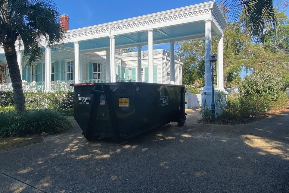 A container in a driveway beside a house