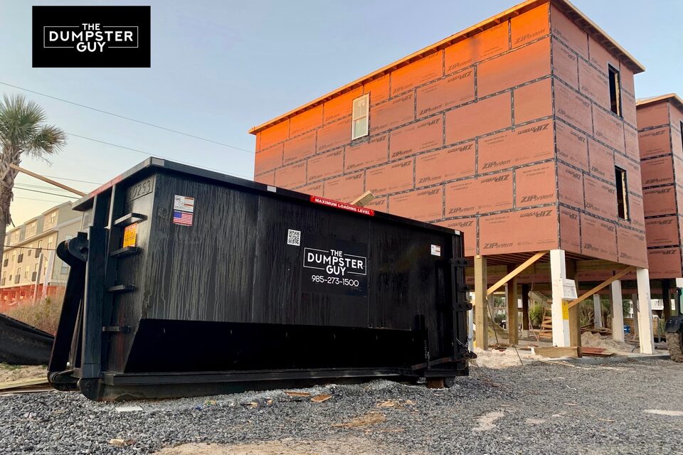 A container standing on gravel beside a house being built