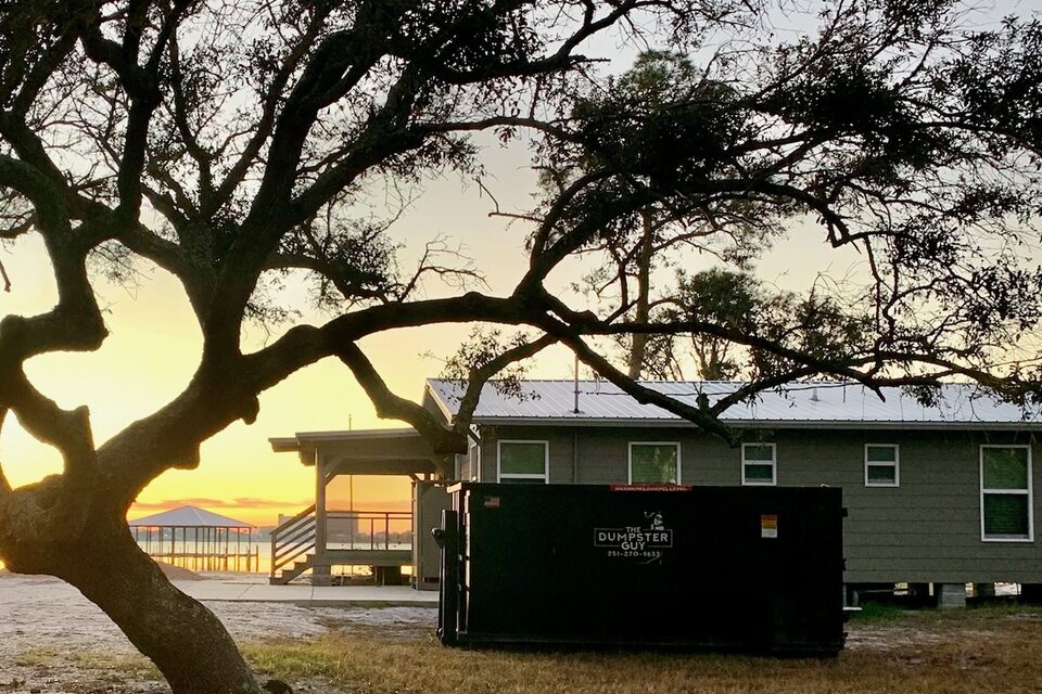 A container beside a cottage under live oaks at sunset